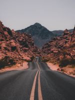 black concrete road surrounded by brown rocks wallpaper