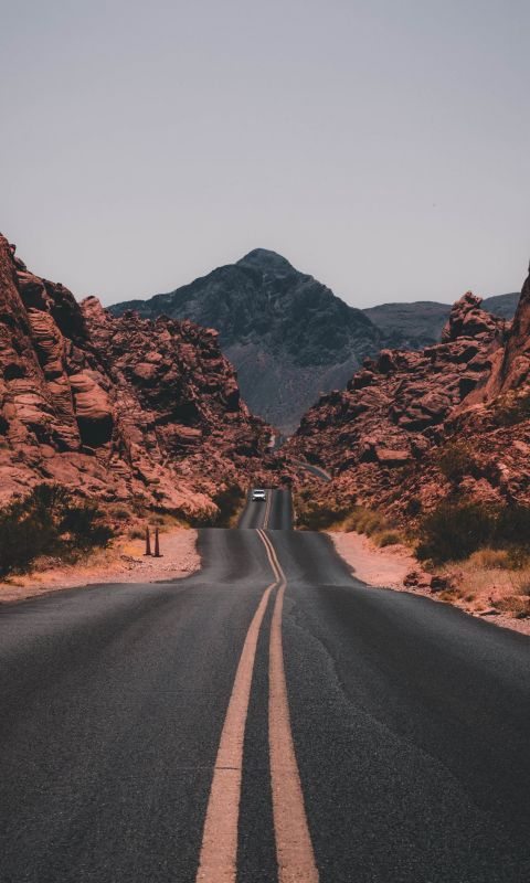 black concrete road surrounded by brown rocks wallpaper