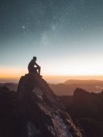 silhouette of person sitting on rock formation dur... wallpaper