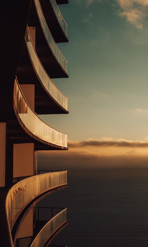 gray painted building and sea ocean wallpaper