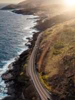 vehicles passing on road beside body of water duri... wallpaper