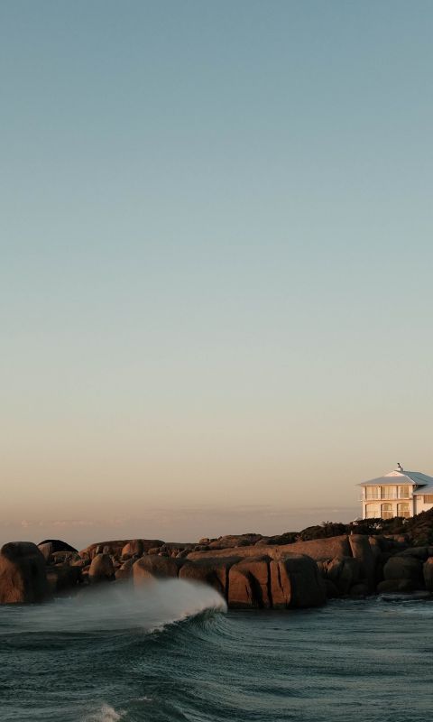 white and brown house on brown rock formation near... wallpaper