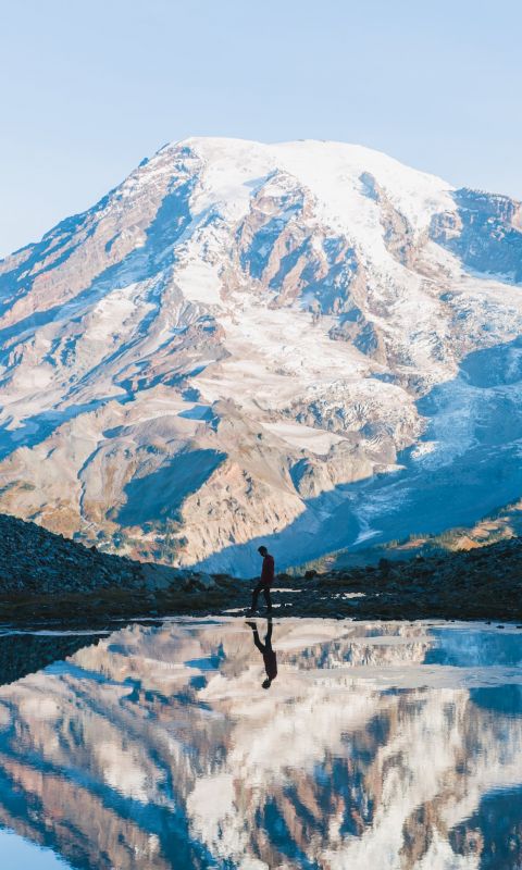 man walking near glacier mountain during day wallpaper