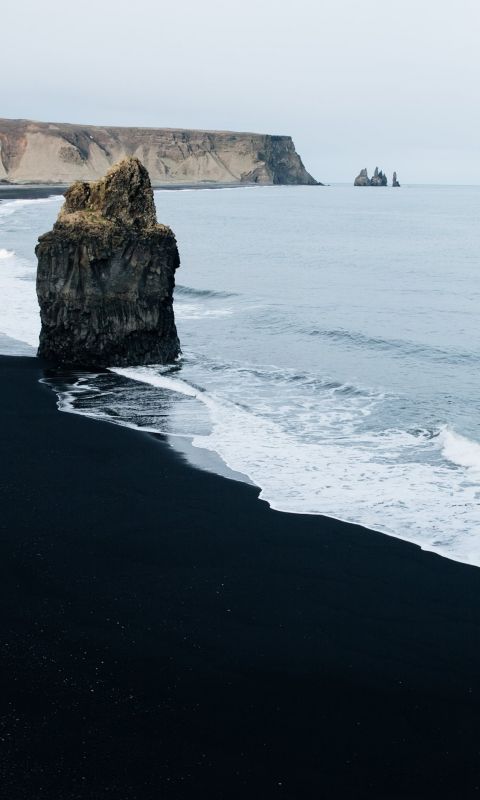 brown monolith rock on seashore wallpaper