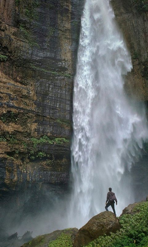 person standing on brown rock formation looking at... wallpaper