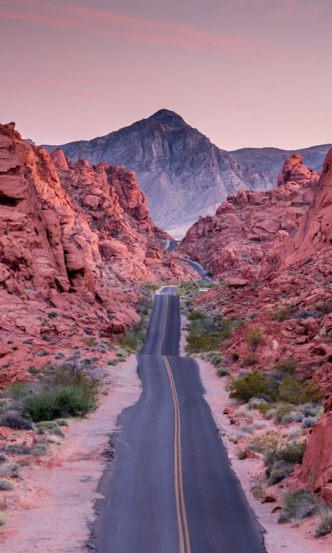 photo of empty road between rock formations wallpaper