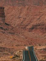 white car on road near brown rock formation during... wallpaper