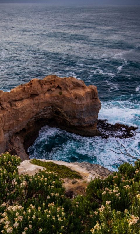 ocean wave crashing on rocky island during day wallpaper