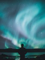 person standing on ground under sky lights wallpaper